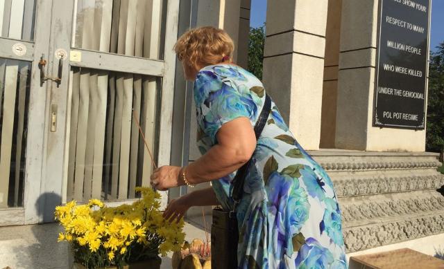 로시타 소리테 비터 윈터 부편집장이 청 아익 탑에 꽃과 향초를 놓고 있다.