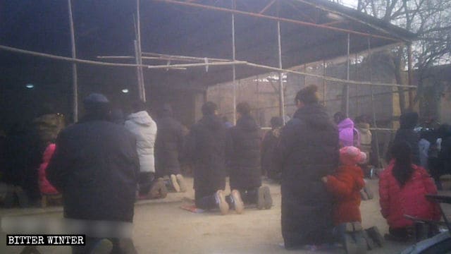 시에장 마을의 야외 미사 중 신자들이 땅에 무릎을 꿇고 있다