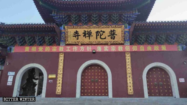 ‘신앙 자유 방침을 이행하라’고 적혀 있는 모순 그 자체의 중공 선전 슬로건이 푸퉈 사원 앞에 걸려 있다