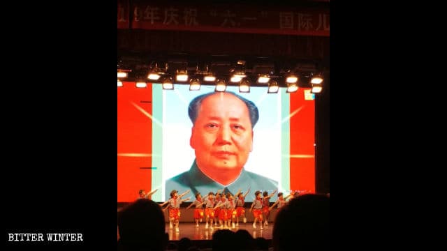 마오쩌둥의 초상화를 배경으로 한 무대에서 ‘붉은’ 공연을 선보이는 아이들