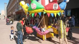 신장 위구르 자치구의 대조적인 광경: 회전목마를 타며 놀고 있는 아이들 뒤로 허톈시(和田市) 시장의 '자경대원들'이 훈련을 하는 모습이 보인다.