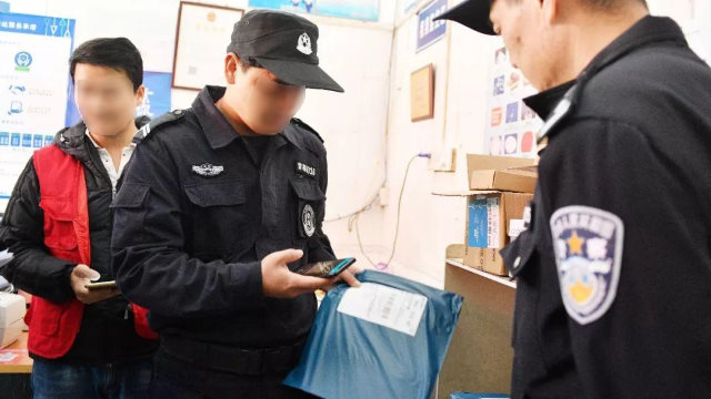 스마트폰 앱으로 배송 물품들을 검사하는 경찰들