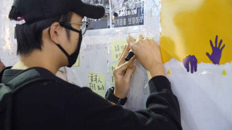 한 시위 참여자가 벽에 홍콩인에 대한 축복을 쓰고 있다