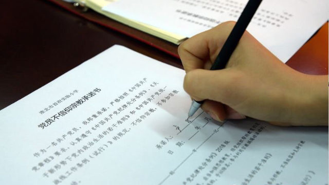 동부 안후이(安徽)성의 화이베이(淮北)캐피털실험초등학교 교사들이 종교를 갖지 않겠다고 약속하는 서약서에 서명하고 있는 모습